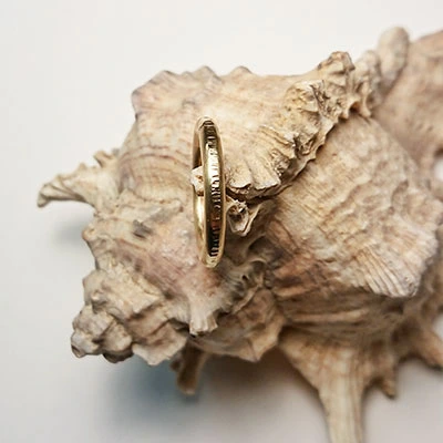 Anneau doré avec motifs présenté sur un coquillage