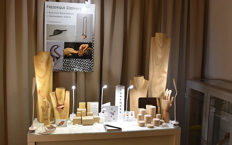 Un stand de bijoux contemporains bien organisé et lumineux sur un marché de créateurs