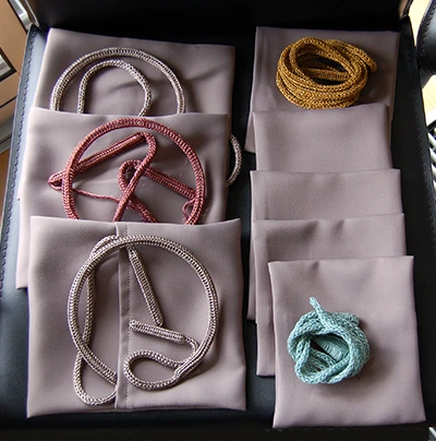 Bracelets et bagues asymétriques colorés et texturés dans des pochon de tissu
