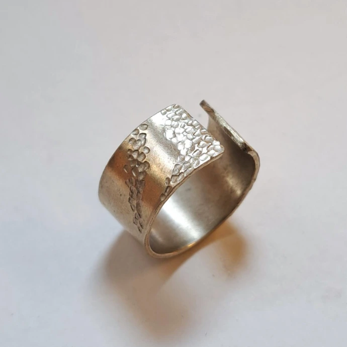création d'élève bague en bandelette large texturée et ciselée en plaque de métal argenté laissée ouverte 