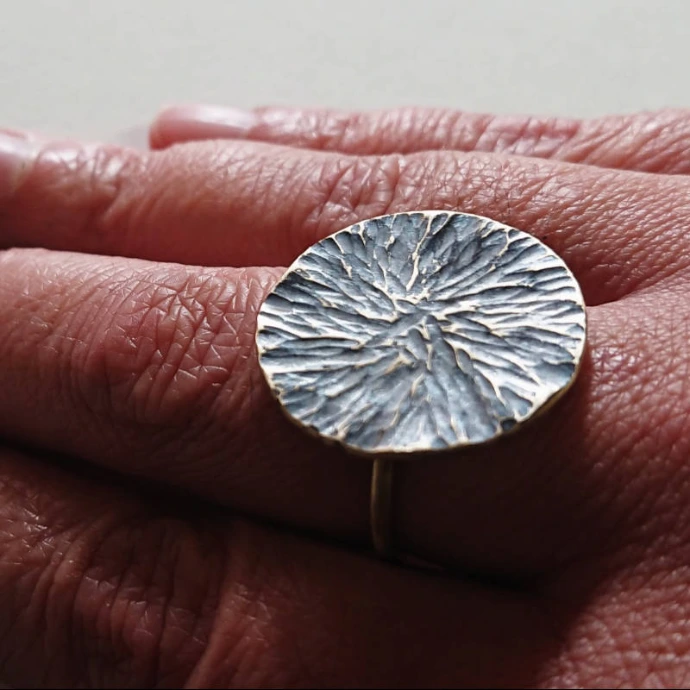 Création d'élève bague texturée martelée et patinée noire portée sur une main
