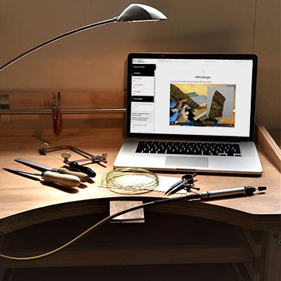 Ordinateur placé sur un établi ouvert sur une page de cours en ligne