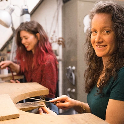 Femme souriante créant des bijoux sur un établi